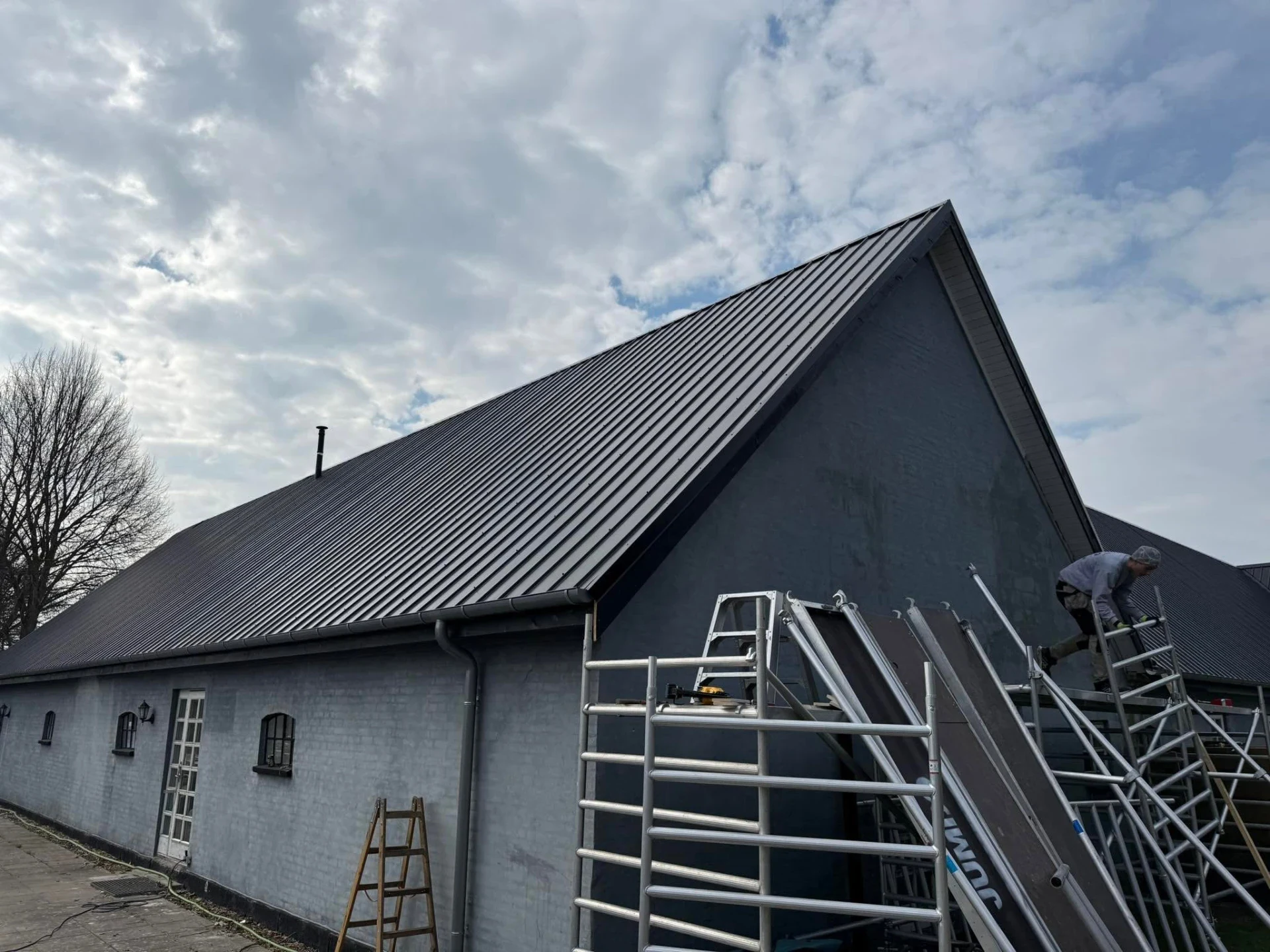 Sort tag på landhus under en skyet himmel.