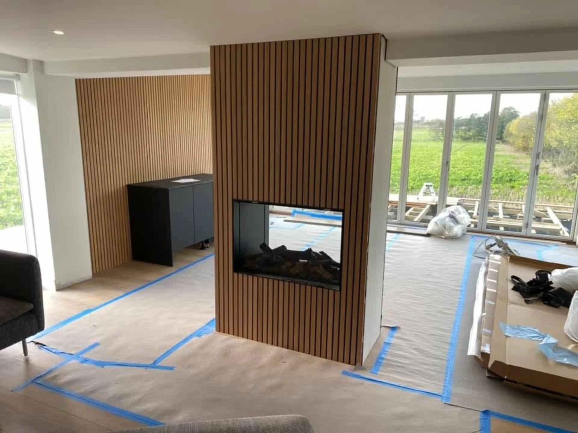 Indendørs moderne pejselement i træ med stor glasfront.