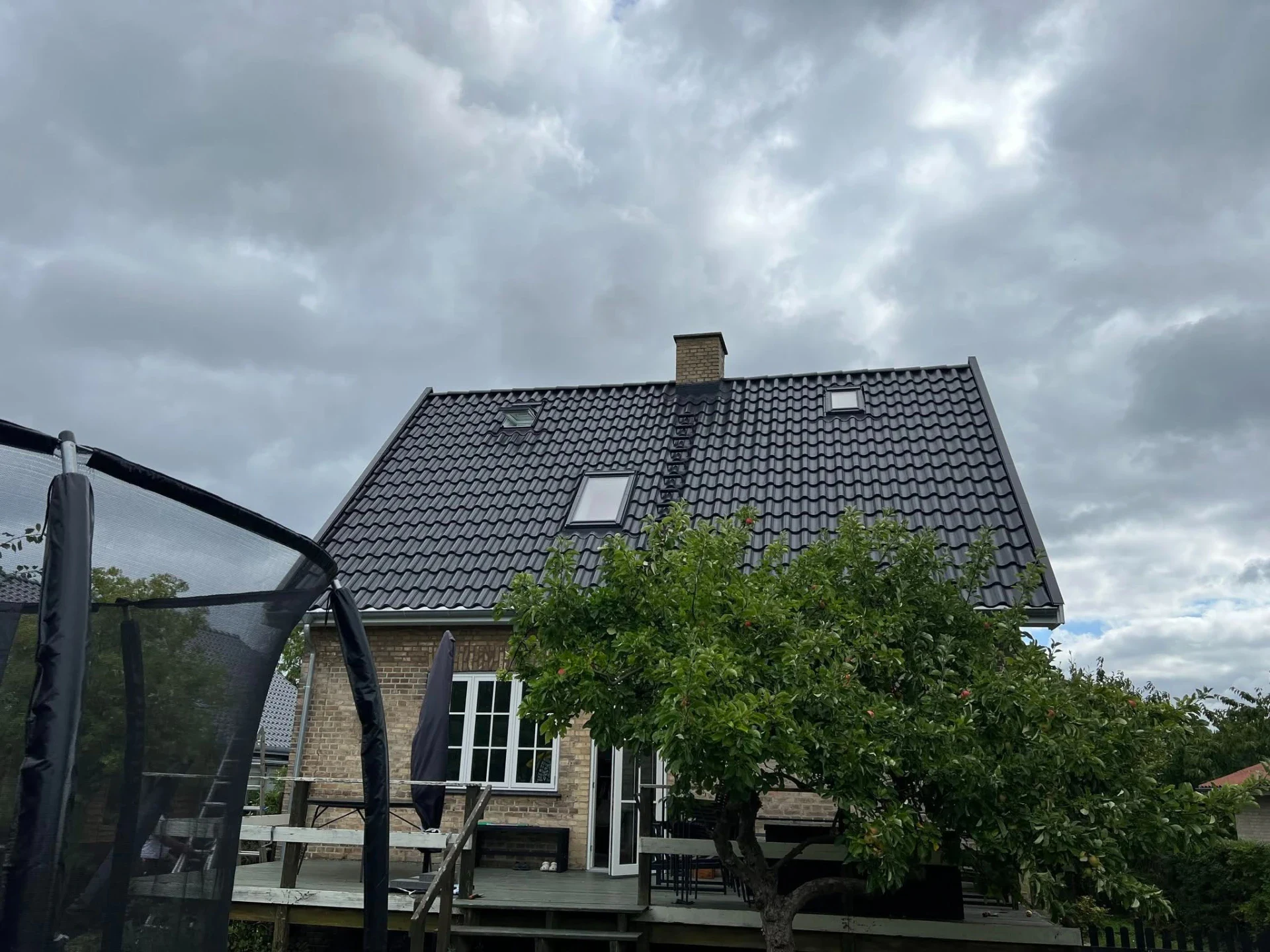 Moderne husbyggeri med tagterrasse og grøn have.