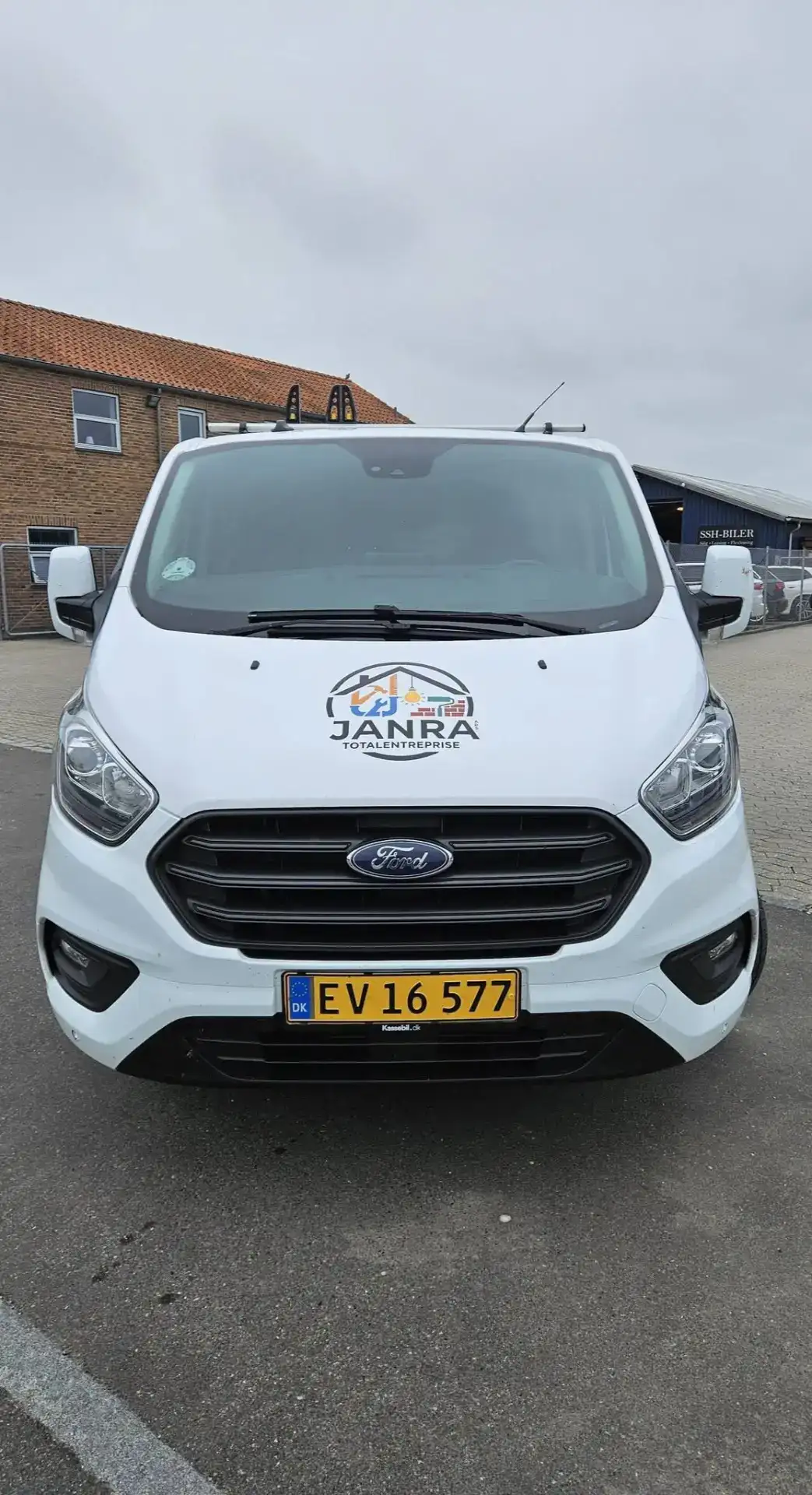 Varebil med JanRa Totalentreprise ApS logo foran en byggeplads.