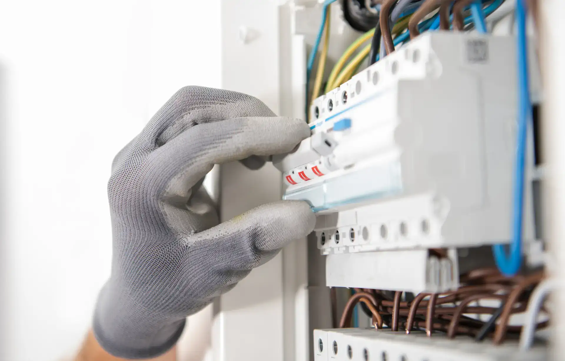 Elektriker installerer eller vedligeholder eltavle med ledninger.